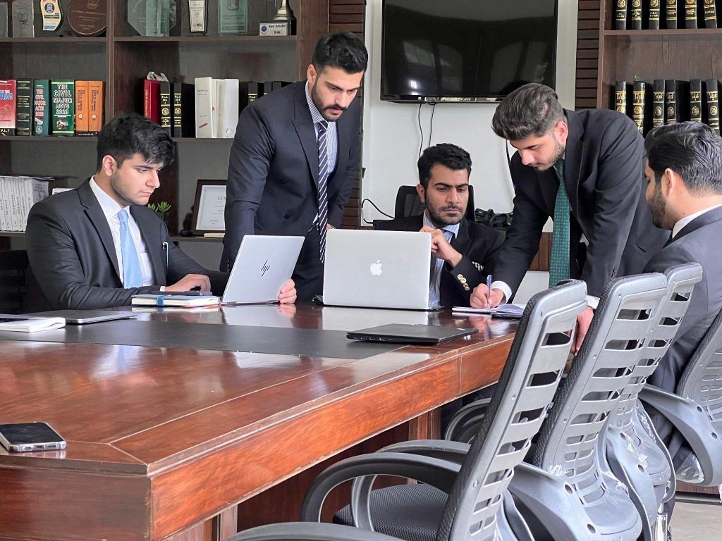 Pakistani legal professionals reviewing documents in an office