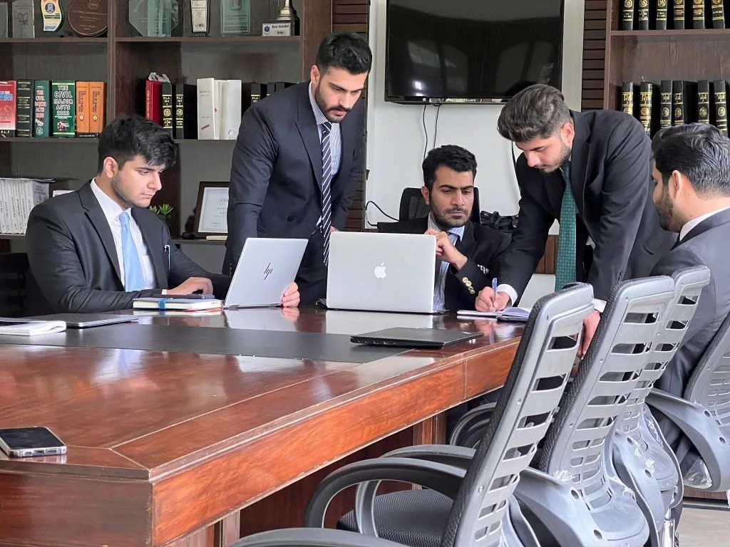 Pakistani legal professionals reviewing documents in a Karachi office